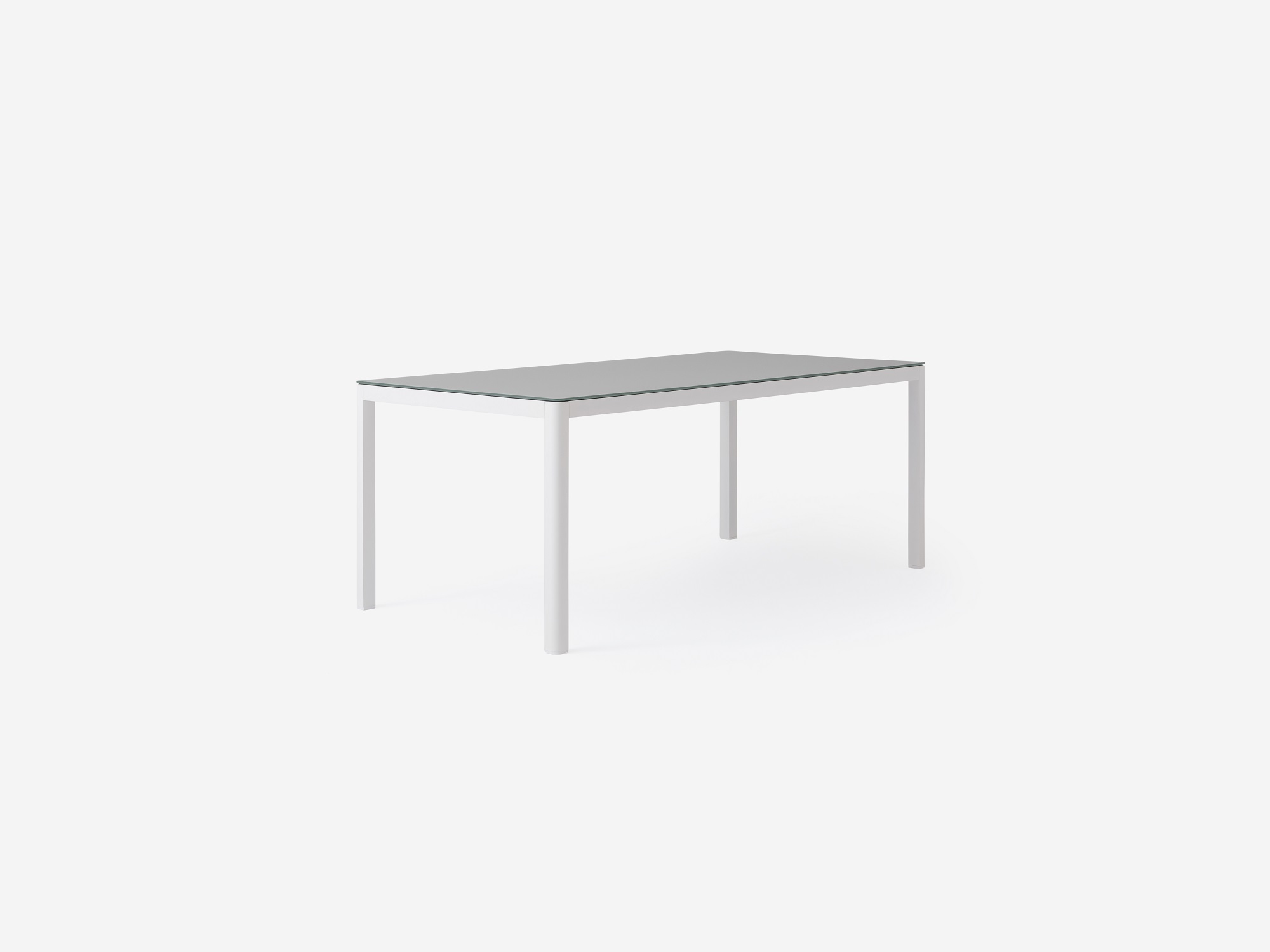 Angled view of the Cape outdoor dining table with a grey glass top and white metal base